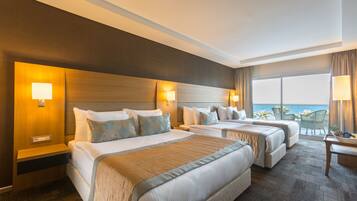 Habitación de hotel con dos camas, una mesita y vista al océano.