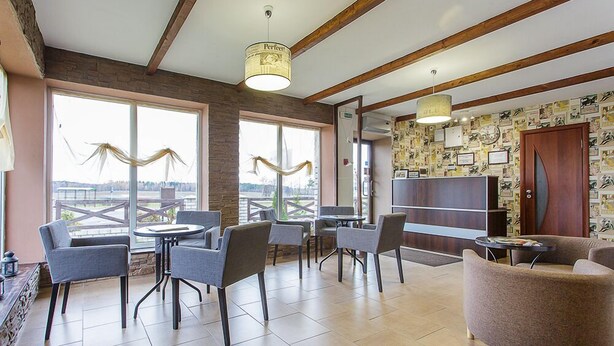 A spacious indoor area with a large window, multiple seating arrangements, and a wall decorated with various items.