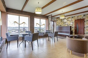 Zona interior àmplia amb una finestra gran, diverses disposicions de seients i una paret decorada amb diferents objectes.