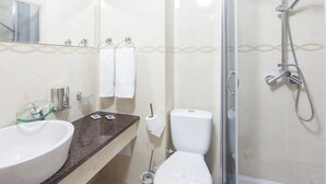 A bathroom with a glass-enclosed shower, a white sink, and a toilet.