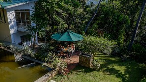 Un patio con piscina, mobiliario exterior y abundante vegetación.