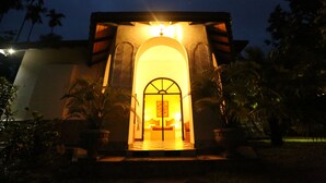 Un edificio con entrada iluminada, piso a cuadros y palmeras.