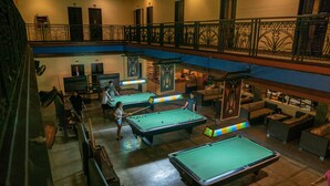 A pool hall with multiple pool tables, a balcony with a railing, and a seating area with couches. - Cebu Westown Lagoon - South Wing (Mandaue)