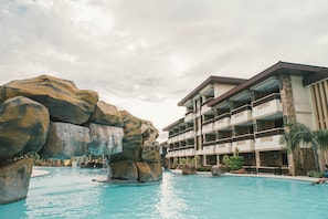 A hotel with a pool area featuring large rock formations and a multi-story building with balconies.