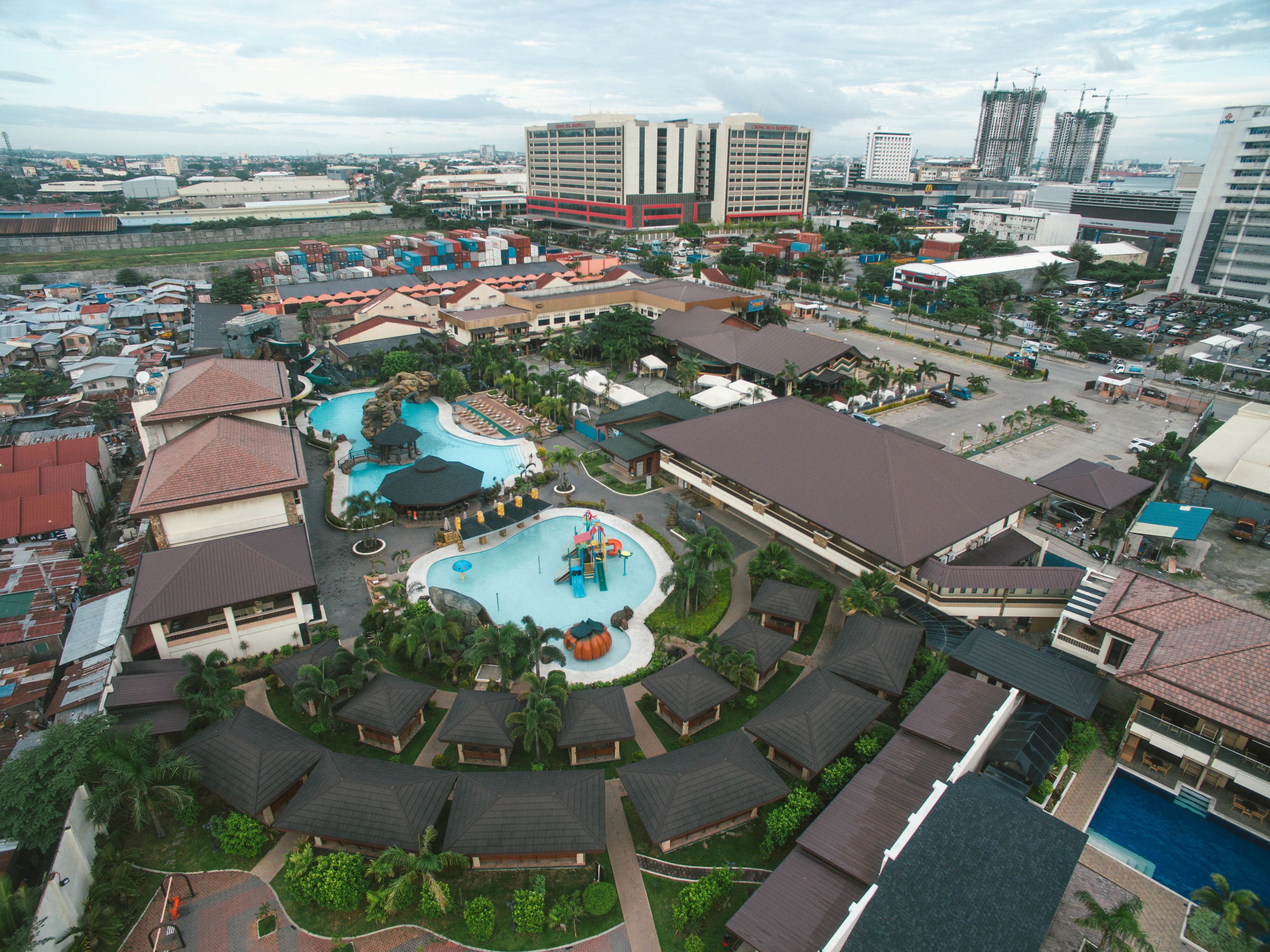 A resort with multiple swimming pools, a large central pool, and a variety of building styles including traditional and modern architecture.