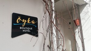 A sign for the boutique hotel 'Öykü' mounted on a white wall. - Oyku Butik Otel (Bozcaada)
