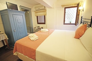 A bedroom with a bed, a wardrobe, a desk, and a window with a view. - Oyku Butik Otel (Bozcaada)