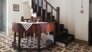A dining area with a wooden table and chairs, a staircase, and a patterned floor. - Oyku Butik Otel (Bozcaada)