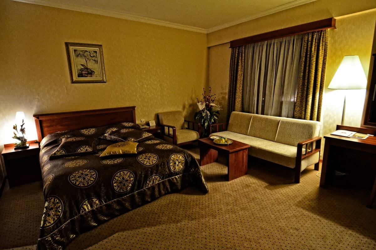 Une chambre d’hôtel avec un lit, un canapé, une table basse, un bureau et une lampe.