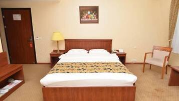 Een hotelkamer met een houten bed, een nachtkastje, een stoel en een schilderij aan de muur.