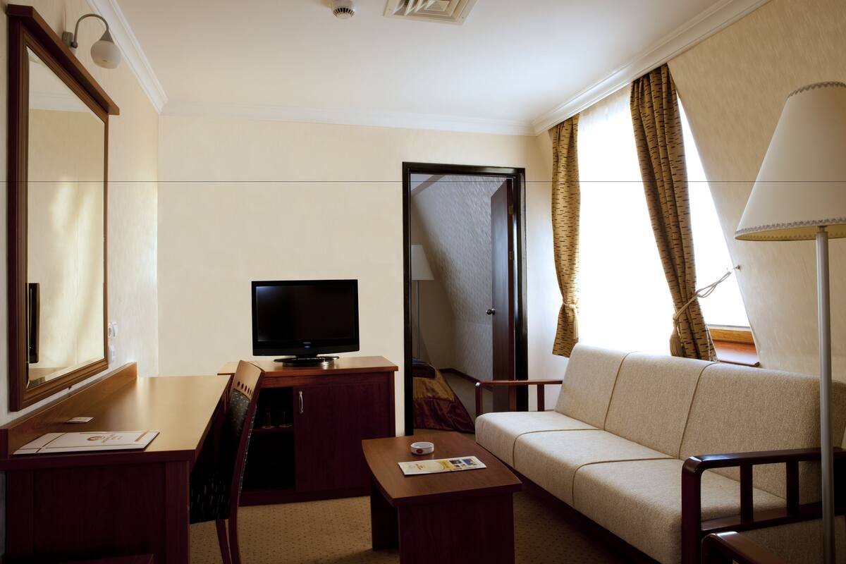 Une chambre d’hôtel équipée d’une télévision, d’un canapé, d’un bureau et d’une lampe.