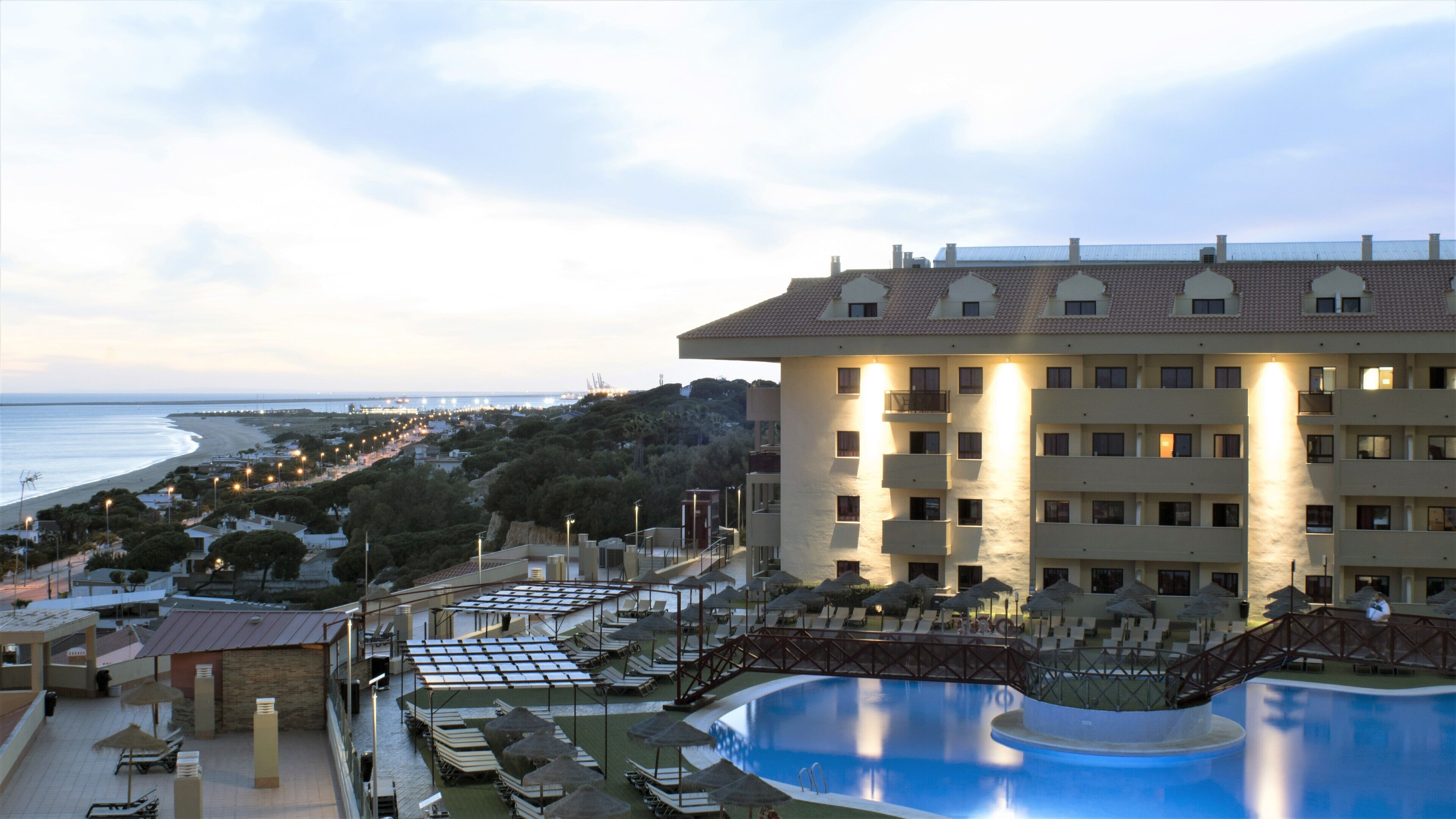 Un hotel con piscina, vistas a la playa y varios balcones.