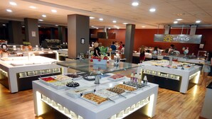 Zona de bufé con varias estaciones de comida, cada una con una variedad de platos y bebidas.