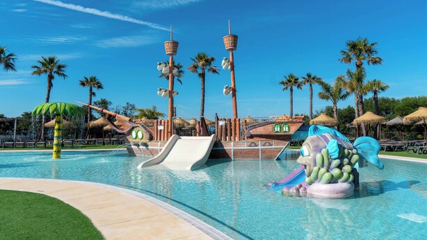 Una piscina con toboganes y una fuente de agua con temática náutica.