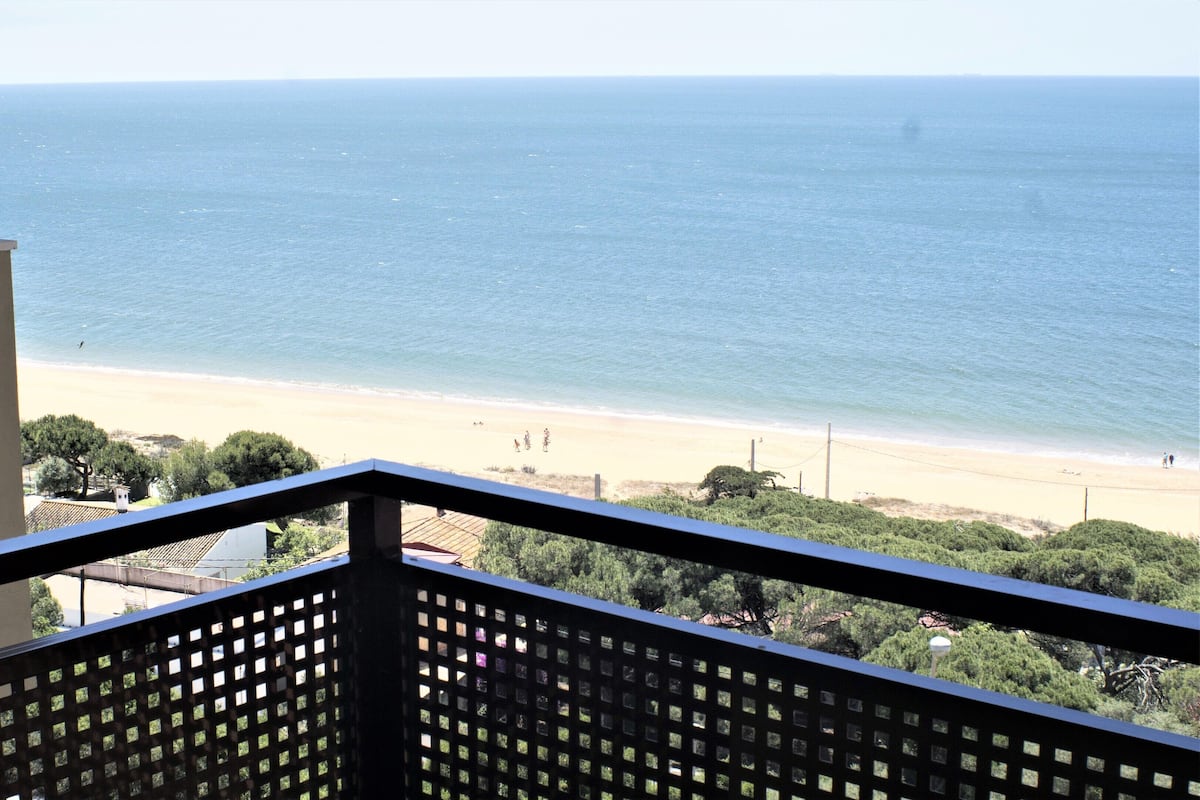 A balcony with a view of a beach and ocean.