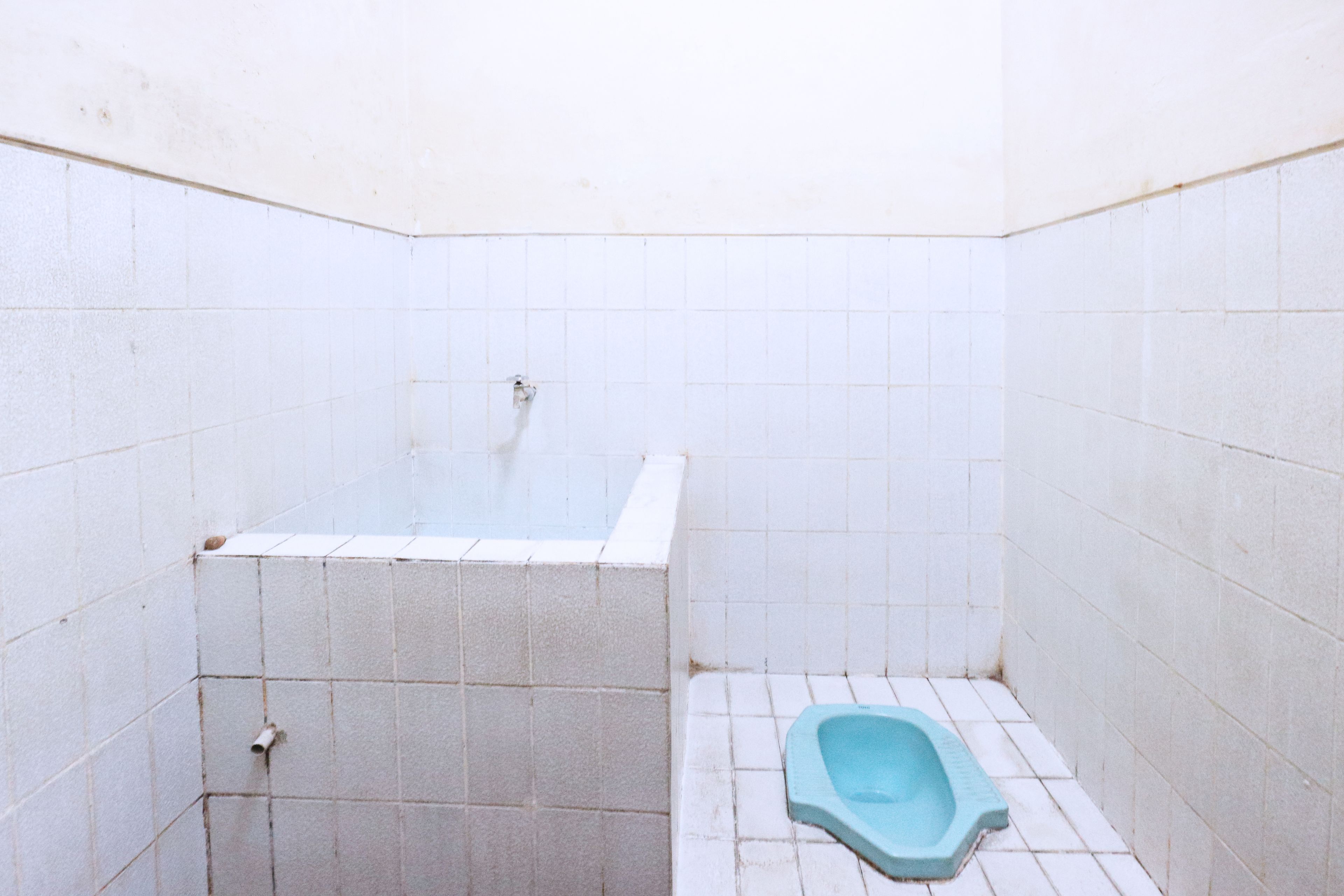 A small, tiled bathroom with a bathtub and a squat toilet.