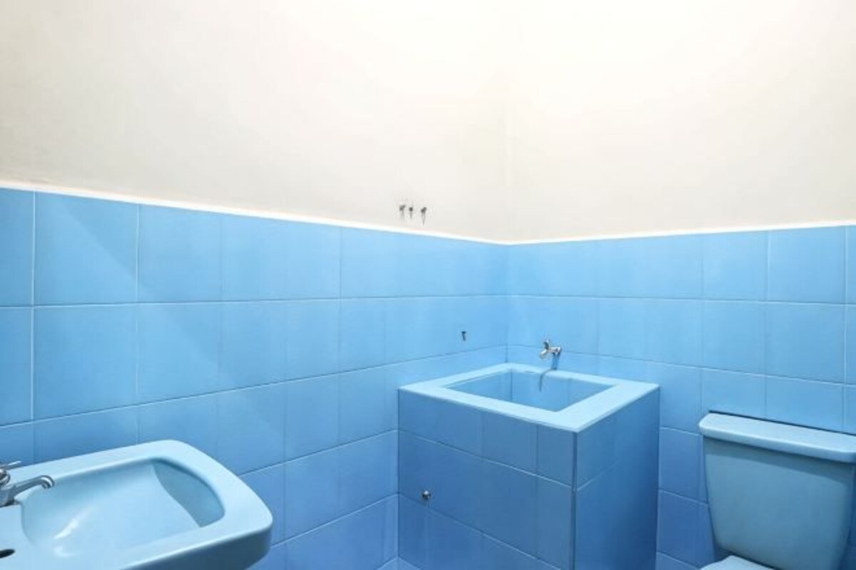 A bathroom with blue tiles, a sink, and a toilet.