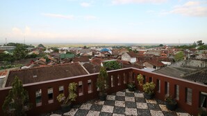 Vista panorámica de un pueblo que combina edificios tradicionales y modernos, un suelo a cuadros y plantas en macetas.