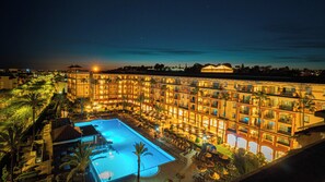 Un hôtel doté de nombreux balcons, d’une piscine et de palmiers.