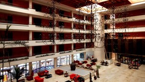 A multi-level atrium with red and white walls, multiple balconies, and hanging chandeliers. - Ohtels Islantilla (Lepe)