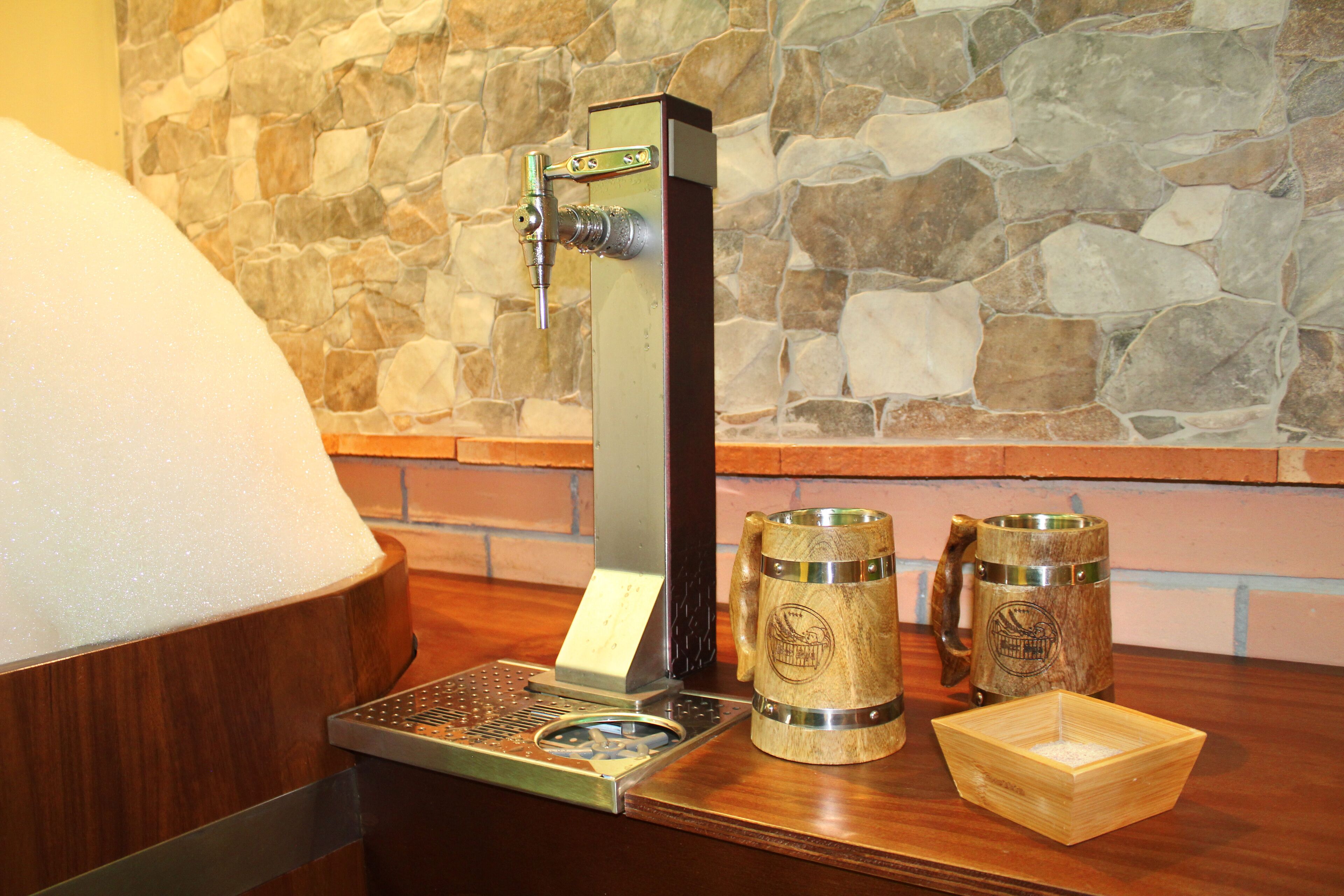 A bar area with a beer tap, two wooden mugs, and a wooden coaster.