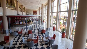 A spacious lobby with a checkered floor, multiple seating areas, and large windows offering views of the outdoors. - Ohtels Islantilla (Lepe)