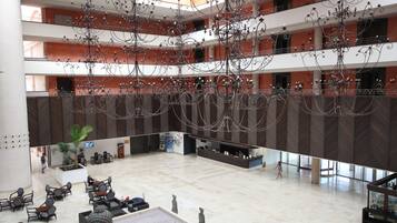 Un hall d’entrée spacieux, doté de plusieurs espaces de détente, d’un comptoir d’accueil et d’un grand lustre décoratif.