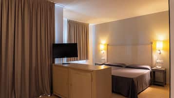 Una habitación de hotel con cama, mesitas de noche, televisor y cortinas.