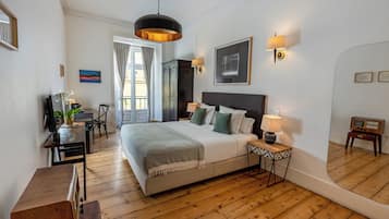 A bedroom with a large bed, bedside tables, a desk, and a chair.