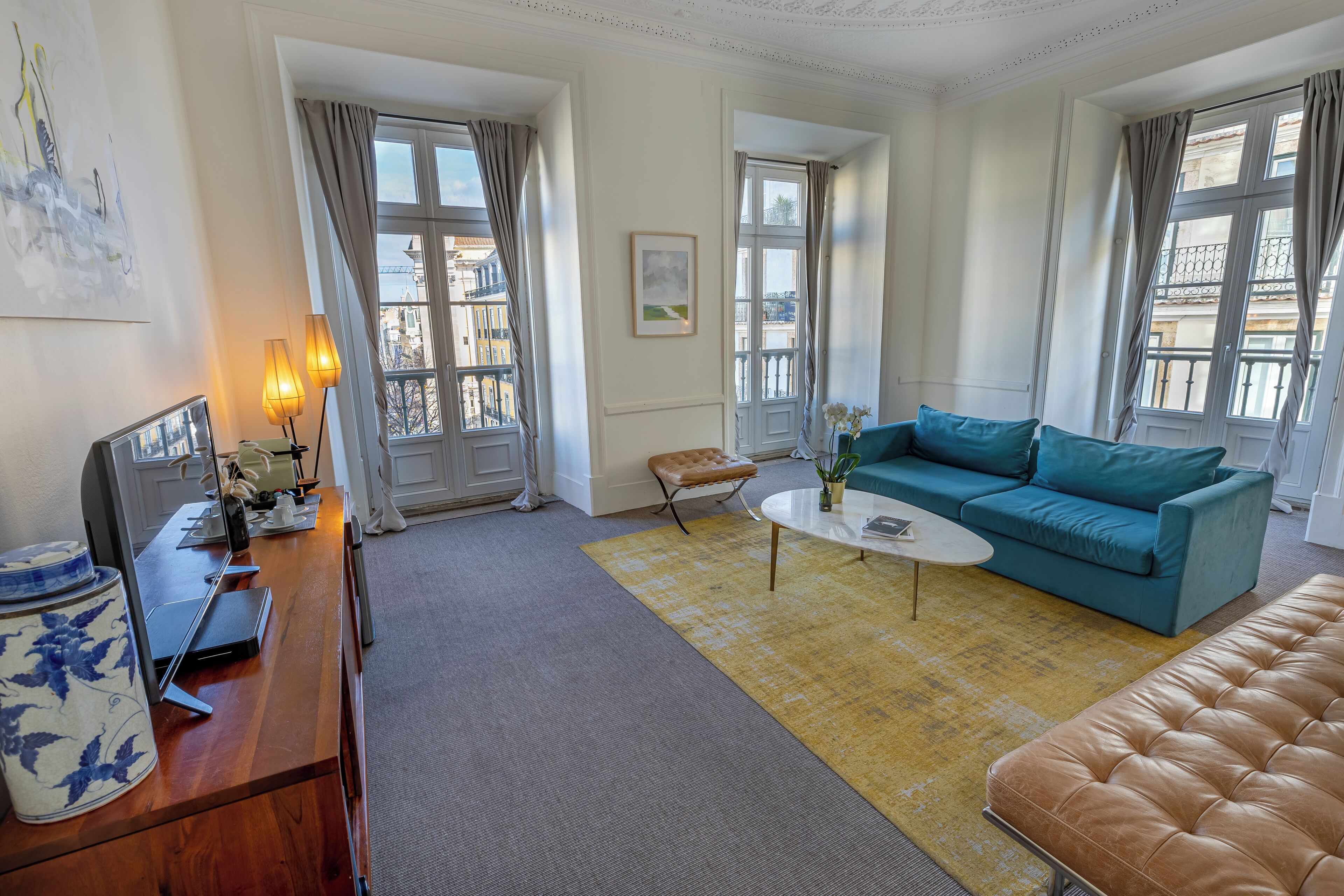 Una sala de estar con un sofá, una mesa de centro, un escritorio de madera con una computadora y vistas a la ciudad a través de amplios ventanales.