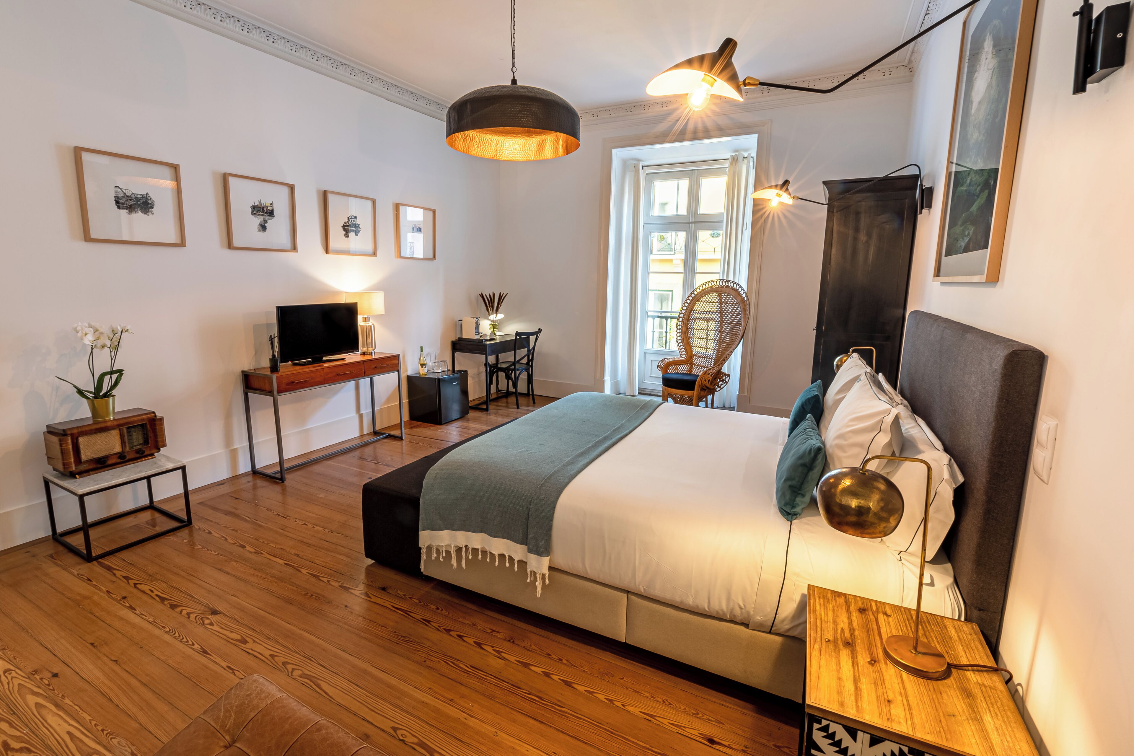 Ein modernes Schlafzimmer mit einem großen Bett, einem Schreibtisch mit Fernseher und einem Essbereich.