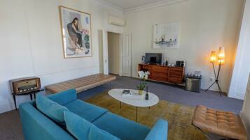 A living room with a blue sofa, a coffee table, a bench, a television, and a cabinet.