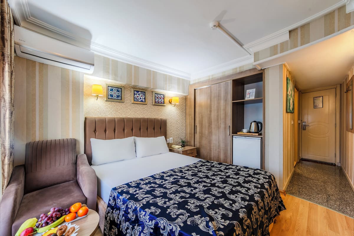 Una habitación de hotel con una cama, una silla, una mesita con fruta, una mesita de noche, un escritorio y un armario.