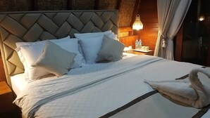 A neatly made bed with white linens and pillows, a decorative swan pillow, and a woven headboard. - Pavilla Labuan Bajo (Labuan Bajo)