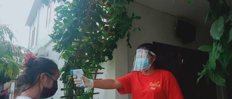 A person in a red shirt holding a thermometer, possibly for temperature checking.