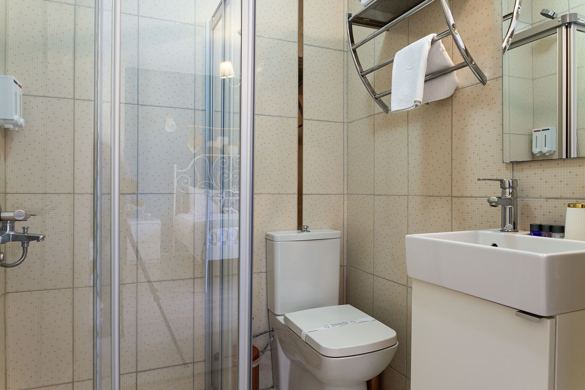 A bathroom with a glass shower enclosure, a toilet, and a sink with a mirror above it.