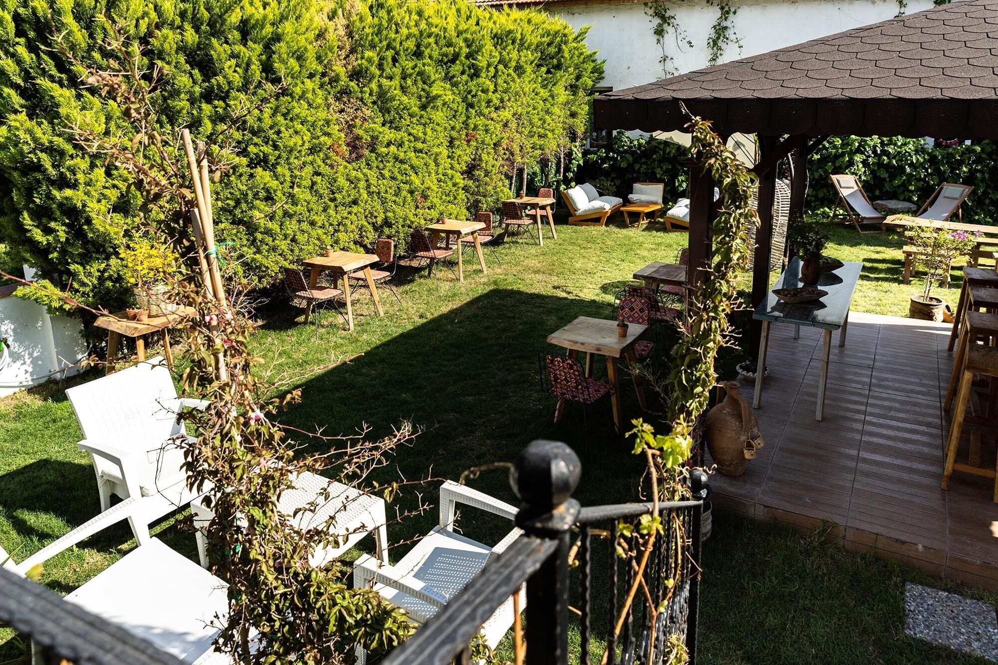 An outdoor patio area with multiple tables and chairs, a wooden pergola, and a view of a lake.