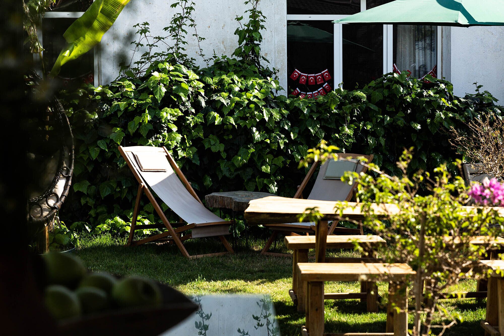 Un jardín con una mesa de madera y dos sillones de descanso.