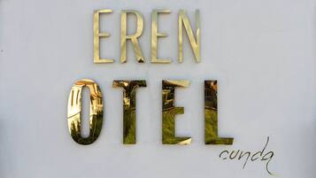 Une enseigne portant les mots « EREN HOTEL » et « cunda », écrits dans une police de caractères stylisée.