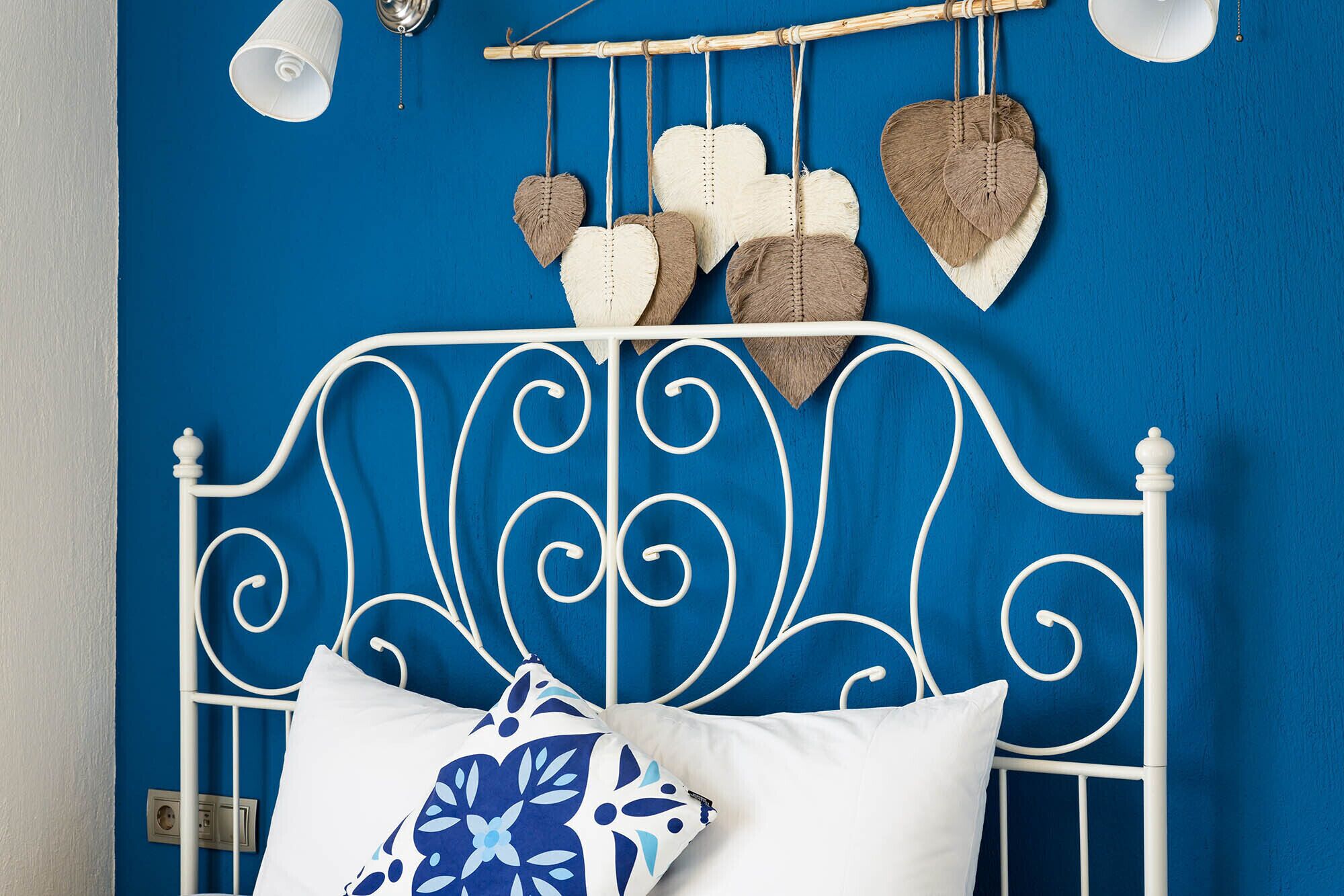 A bed with a white metal frame, a white pillow, and a blue and white patterned pillow.