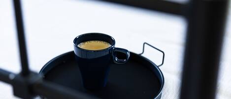 Una taza de café sobre una bandeja dentro de una habitación con estructura metálica.