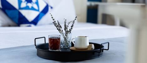 Una bandeja con una taza de té, una taza de café y un florero con lavanda sobre una cama.