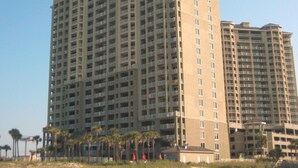 Ein hoch aufragendes Hotel mit mehreren Etagen und Balkonen, in Strandnähe gelegen.