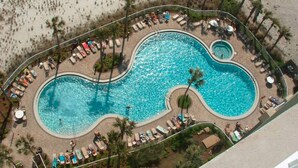 Ein großer Pool mit mehreren Bereichen, umgeben von Liegestühlen und Palmen.