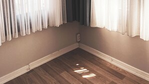 A corner room with a wooden floor, a white baseboard, and a window with sheer white and dark gray curtains. - Piya Boutique Hotel (Istanbul)