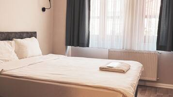 Un dormitorio con una cama grande, un radiador y una ventana con cortinas.