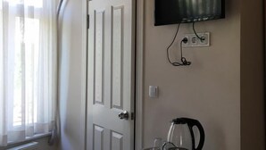 A room with a white door, a mounted TV, an air conditioning unit, and a coffee maker on a cabinet. - Piya Boutique Hotel (Istanbul)