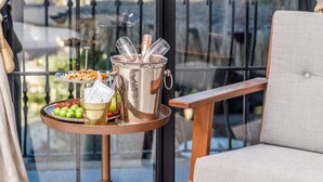 Un balcón con mesa dispuesta con comida y bebidas, una silla y vista al puerto deportivo.
