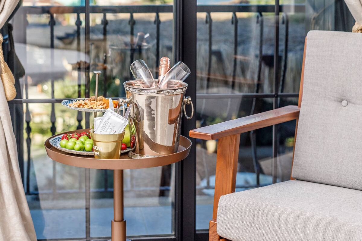 Un balcón con mesa dispuesta con comida y bebidas, una silla y vista al puerto deportivo.