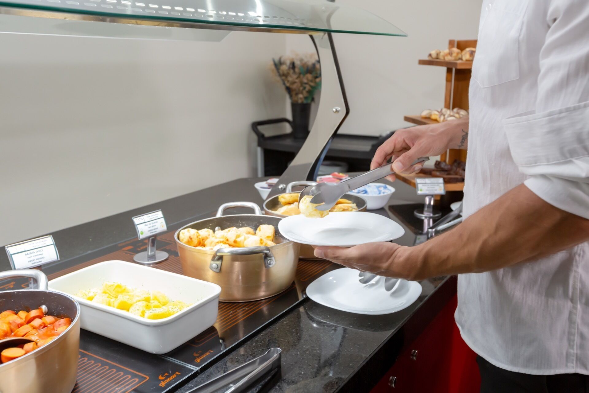 Un buffet proposant divers plats, avec une personne chargée de servir les aliments.